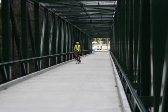 A cyclist using the Good Neighbor Trail bridge next to Broad Street over the railroad tracks (5.22.2024 photo)