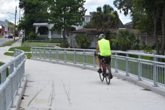 A cyclist exiting the Good Neighbor Trail bridge over the railroad tracks heads toward downtown Brooksville (5.22.2024 photo)